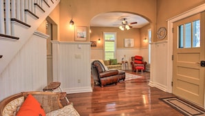 A spacious living room with hardwood flooring, a leather recliner, a wicker chair, and a red armchair. A staircase with white railings leads to another level. - Ely Getaway Near Town, Lakes, & Outdoor Recreation (Ely)