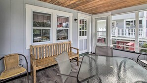 A covered porch with a wooden bench, a glass table, and a wicker chair. - Homey Laconia Home w/ Private Porch & Grill (Laconia)