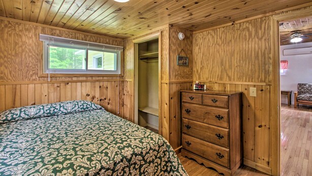 A wooden-paneled room with a bed, a dresser, and a window. - Homey Laconia Home w/ Private Porch & Grill (Laconia)