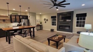 A modern kitchen with dark cabinets, a central island, and bar stools. - Private Guesthouse close to Nashville (Mt. Juliet)