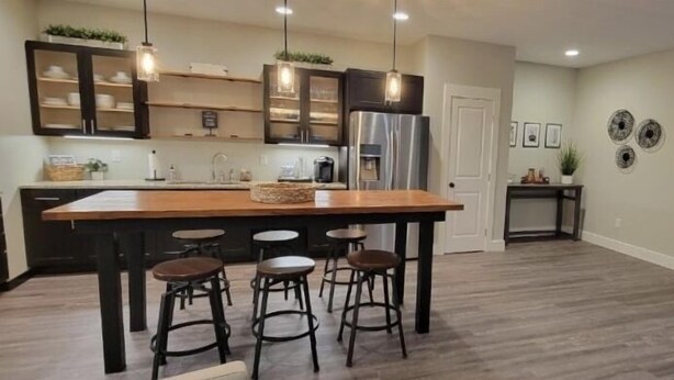 A modern kitchen with a central island, bar stools, pendant lighting, and a stainless steel refrigerator. - Private Guesthouse close to Nashville (Mt. Juliet)