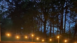 An outdoor seating area with a stone wall, string lights, and cushioned furniture. - Private Guesthouse close to Nashville (Mt. Juliet)