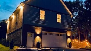 A two-story house with a garage, illuminated windows, and a driveway. - Private Guesthouse close to Nashville (Mt. Juliet)