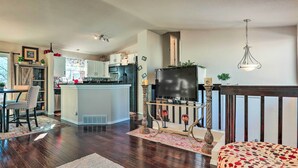 Amplia sala de estar con un televisor grande, una mesa de comedor con sillas y una cocina al fondo.