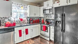 Una cocina moderna con armarios blancos, electrodomésticos de acero inoxidable y una toalla roja colgada en la puerta del horno.