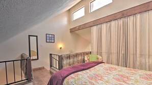 A bedroom with a large bed, a window, a wooden ceiling, and a view of the outdoors. - Quaint Angel Fire Townhome: 1/2 Mi to Ski Slopes! (Angel Fire)