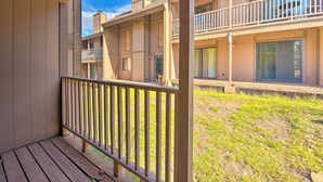 A multi-story residential building with balconies, a wooden deck, and a grassy yard. - Quaint Angel Fire Townhome: 1/2 Mi to Ski Slopes! (Angel Fire)