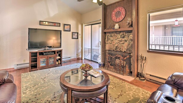 A living room with a television, leather sofa, a glass coffee table, a fireplace, and a balcony view. - Quaint Angel Fire Townhome: 1/2 Mi to Ski Slopes! (Angel Fire)