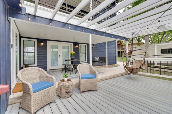 A covered outdoor deck with wicker furniture and a table, overlooking a backyard.