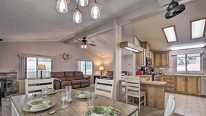 Amplia sala de estar con una mesa de comedor para cuatro, chimenea y cocina con armarios de madera y microondas.