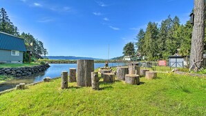 Une propriété au bord du lac, dotée d’une pelouse, de souches d’arbres, d’un quai et d’une maison avec un toit bleu.