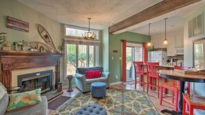 A cozy living room with a fireplace, a sofa, and a dining area with red chairs. - Wintergreen Resort Mountain Condo w/ Pool Access! (Nellysford)