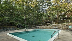 A rectangular swimming pool with a stone border, surrounded by a wooden deck and lounge chairs. - Wintergreen Resort Mountain Condo w/ Pool Access! (Nellysford)