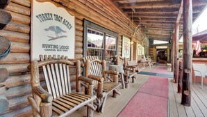 A log cabin-style building with wooden benches and a sign reading "Turkey Trot Acres Hunting Lodge".