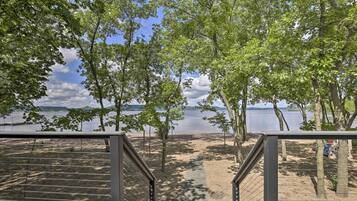 Step onto the shaded deck and walk to the sandy beach surrounded by lush greenery.