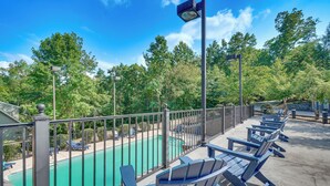 A rooftop pool area with a view of a swimming pool, lounge chairs, and a railing.