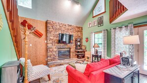 A cozy living room with a stone fireplace, a red sofa, and a wooden coat rack.