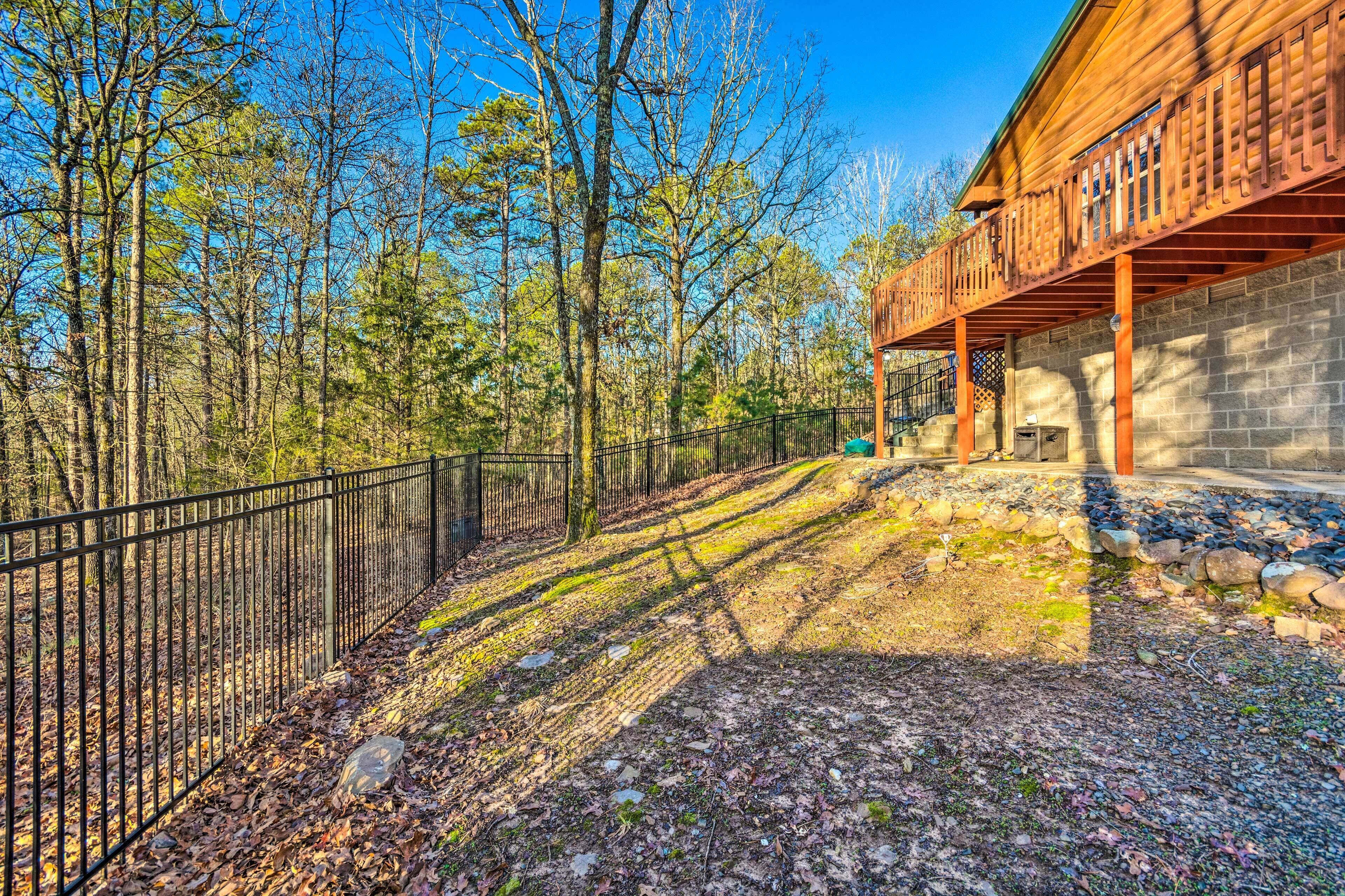 A wooden cabin with a balcony, surrounded by a forest.
