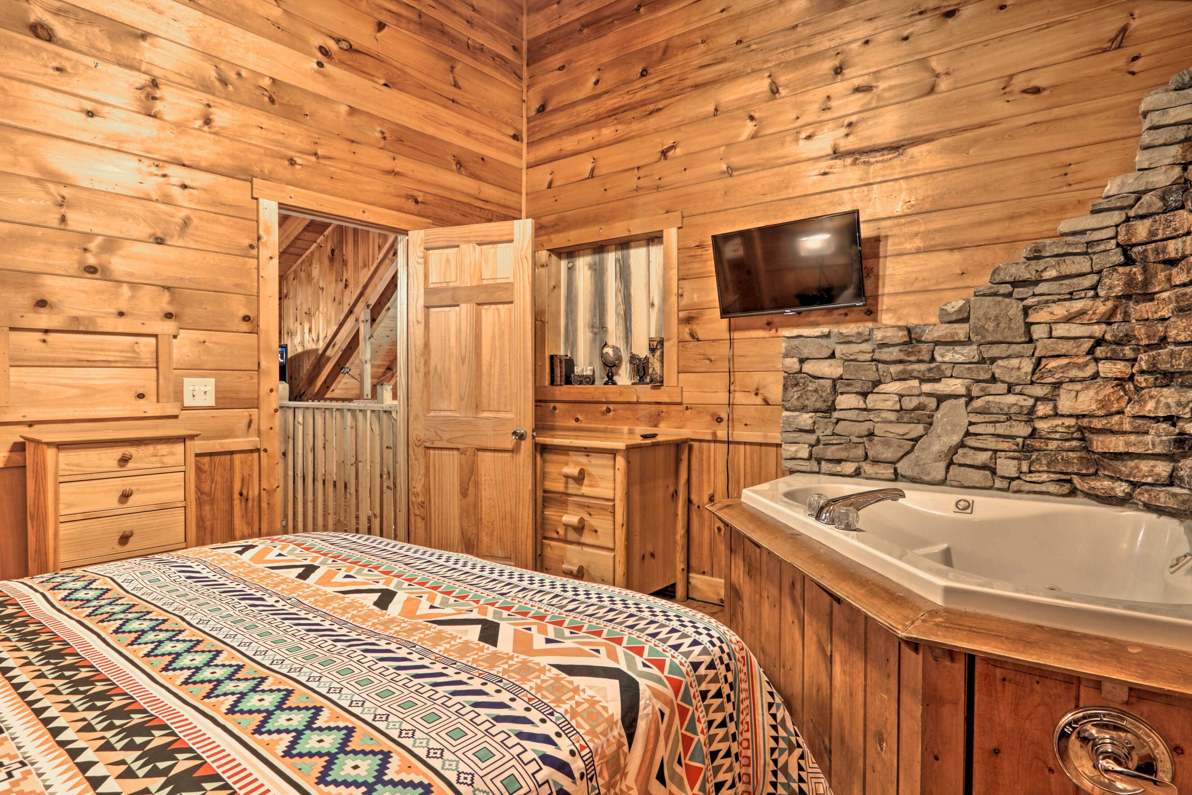 A wooden cabin interior with a bed, a stone wall, a wooden cabinet, and a bathtub.