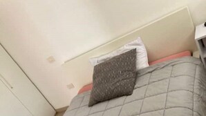 A neatly made bed with a grey quilt and a grey pillow, wooden flooring, and a white wardrobe. - house-parking-wifi-adige muse (Trento)