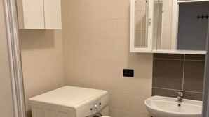 A compact bathroom with a washing machine, a sink, and a cabinet. - house-parking-wifi-adige muse (Trento)