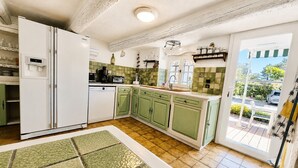 Une cuisine équipée d’un réfrigérateur, d’un lave-vaisselle et de meubles de rangement verts.