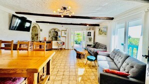 A cozy, well-lit room with a wooden dining table, a sofa, and a television mounted on the wall. - the sea while the legendary country's calm (le beausset)