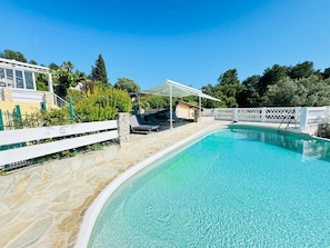 A clear blue swimming pool with a stone deck, a white fence, and a covered seating area. - the sea while the legendary country's calm (le beausset)