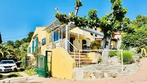 A yellow house with a covered porch and a staircase leading to the entrance. - the sea while the legendary country's calm (le beausset)