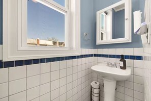 A bathroom with a window, a sink, and a mirror. - Charming DC Rowhome w/ Off-Street Parking, Metro Access & Walkable to Everything (Washington)