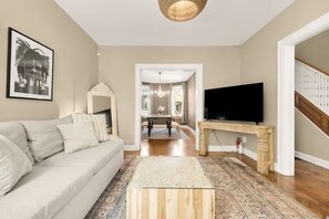 A living room with a sofa, a TV, a wooden coffee table, and a patterned rug.