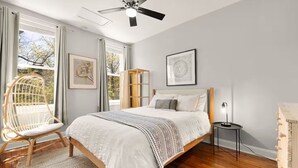 Ein Schlafzimmer mit Bett, Sessel, Nachttisch und Deckenventilator.