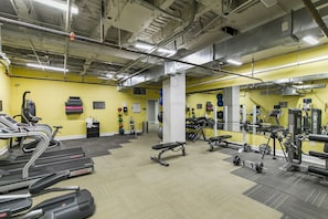 Une salle de sport équipée de tapis de course, d’appareils de musculation et d’un mur entièrement recouvert de miroirs.