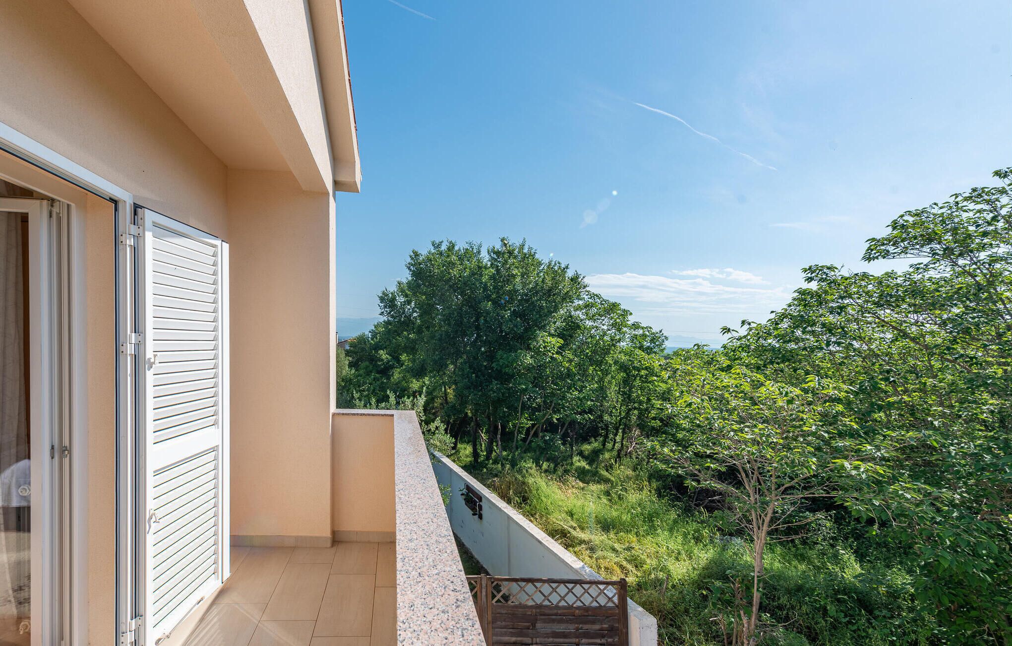 Un balcon donnant sur un paysage verdoyant et luxuriant, avec de nombreux arbres.