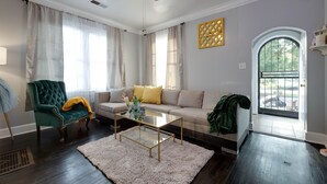 A living room with a green armchair, a beige sofa, a glass coffee table, and a white rug. - Midtown Home Away From Home ShellCrestCorp 743 (Memphis)