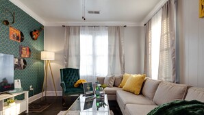 A living room with a sofa, a green armchair, a coffee table, and a television. - Midtown Home Away From Home ShellCrestCorp 743 (Memphis)