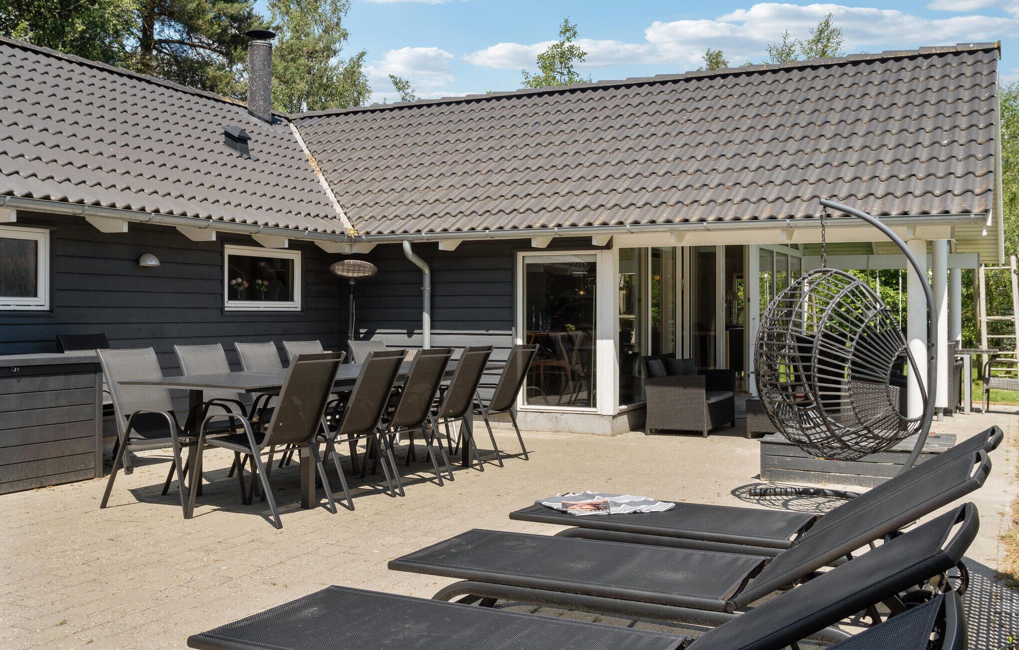 Eine Terrasse im Freien mit überdachter Sitzgruppe, einer Hängematte und einem Grill.