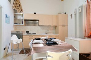 A compact kitchen with a dining table, chairs, and a refrigerator. - LOFT ATMOSPHERA TRENTOCENTRO-CIPAT022205-AT-066735 (Trento)