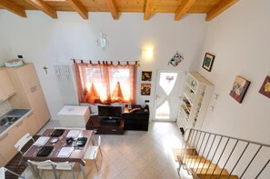 A compact living space with a dining area, kitchenette, and a staircase leading to an upper level. - LOFT ATMOSPHERA TRENTOCENTRO-CIPAT022205-AT-066735 (Trento)
