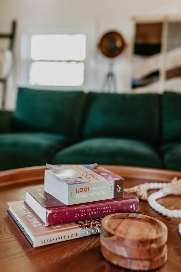 A stack of books on a wooden tray with a wooden bowl and a string of beads.