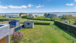 Ett bostadsområde med hus, en liten trädgård och utsikt över havet.