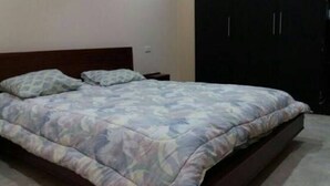 A bedroom with a bed, pillows, a nightstand, and a wardrobe. - Departamento en Manta Frente al mar (Manta)