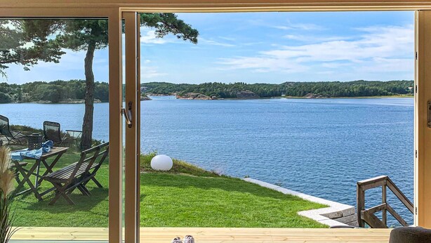 Una habitación con un amplio ventanal corredera que da a una terraza con vistas a un lago.
