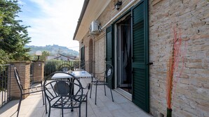 An outdoor patio with a table and chairs, a brick wall, and a view of a hill in the background.