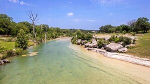 A river with clear water, surrounded by greenery and rocks. - Welcome to the Ladybug Walk DT and Blanco River (Wimberley)