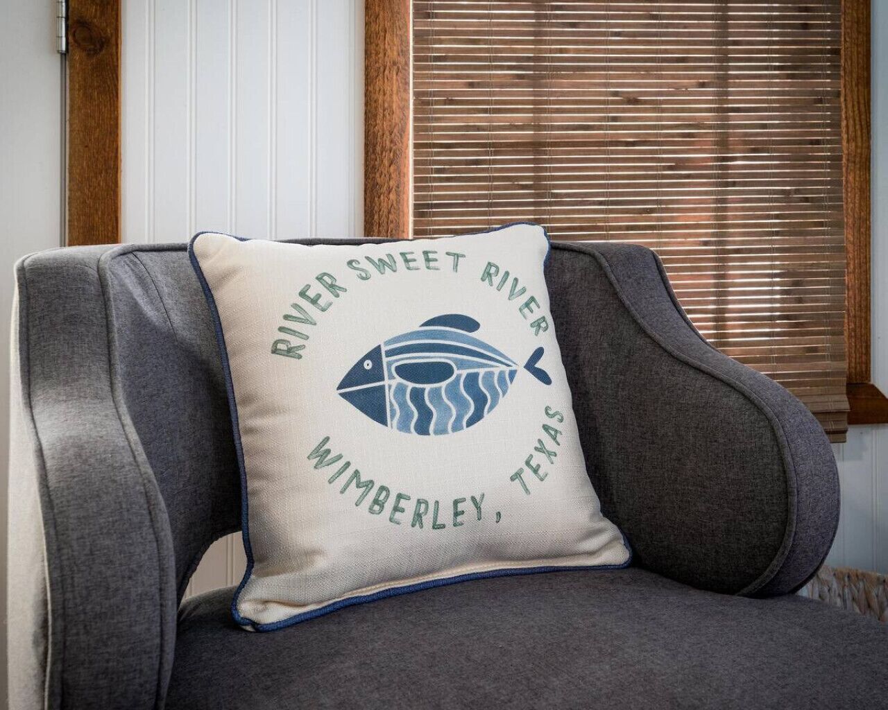 A chair with a pillow featuring a fish and text.