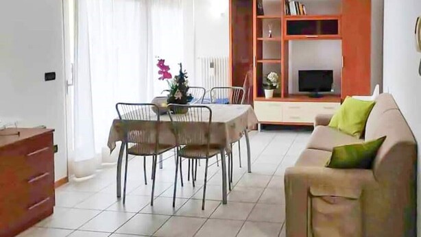 Un salon comprenant un canapé, une table à manger avec des chaises et un meuble TV avec des étagères.