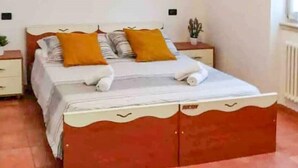 Une chambre avec un lit en bois, des murs blancs et une décoration en forme d’étoile sur le mur.