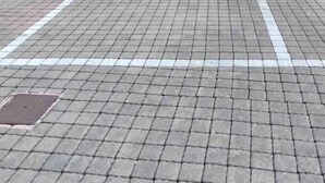 Un bâtiment doté de trois fenêtres et d’une aire de stationnement dallée.