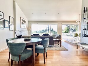 Un salon moderne avec un coin repas, de grandes fenêtres et une cheminée.